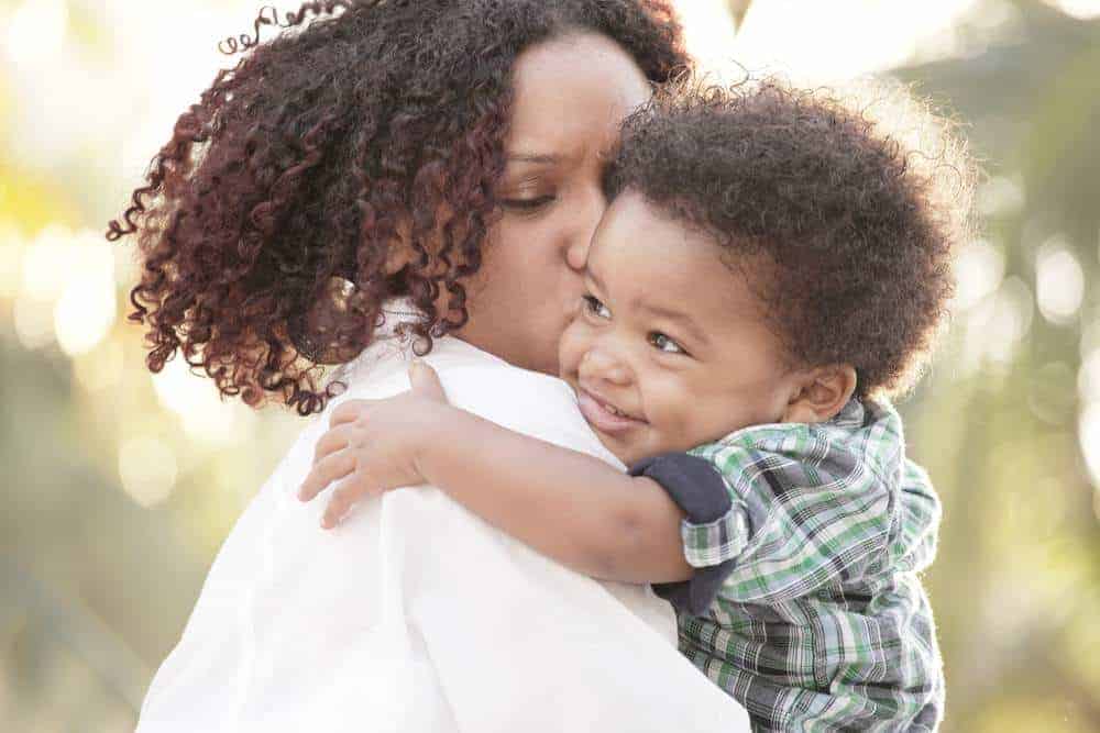 Woman holding her son and kissing him on the cheek. The post lists Encouraging Bible Verses.