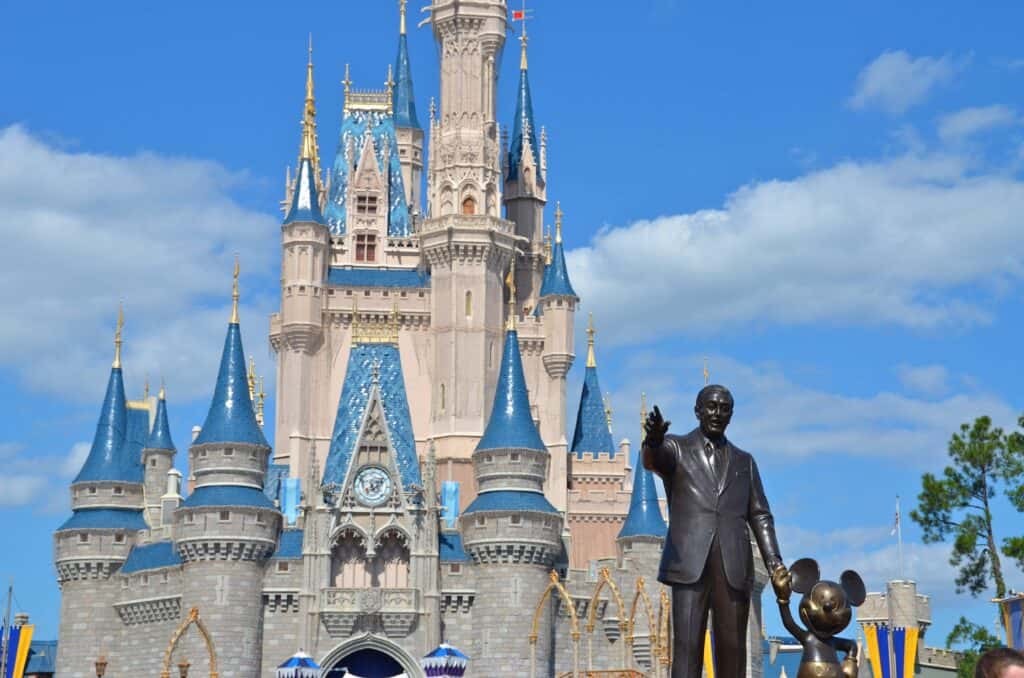 statue of walt disney and mickey in front of the Magic Kingdom Castle.