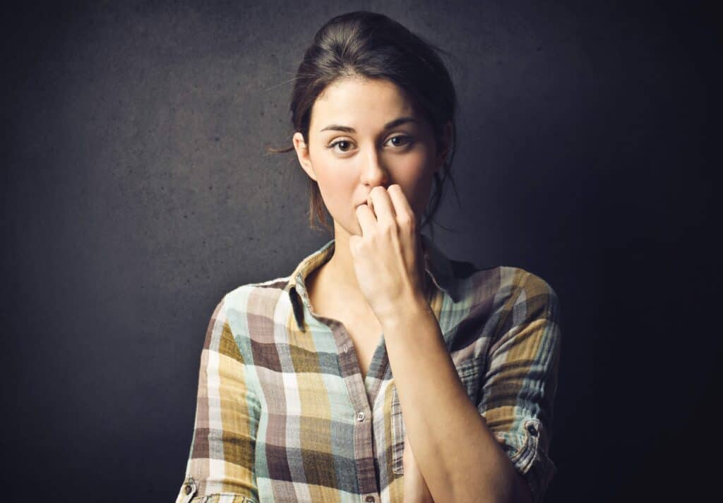 woman with her hand to her mouth looking worry, filled with fear