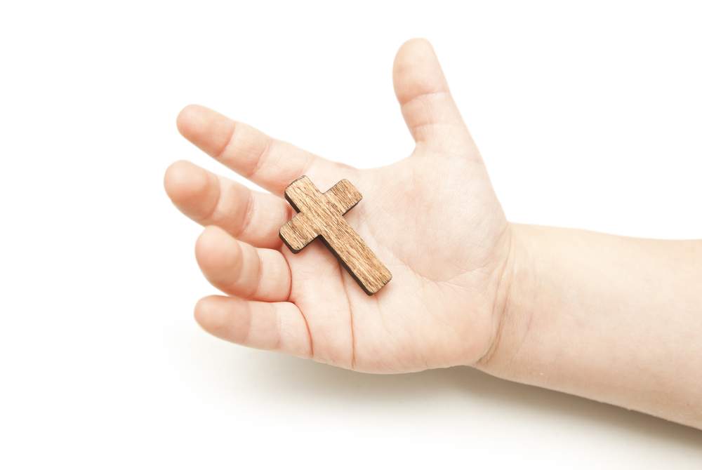 A little wooden cross in the child's hands