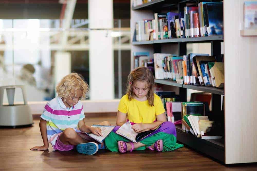 Child in school library. Kids read books. Little girl and boy reading and studying. Children at book store. Smart intelligent preschool kid choosing books to borrow.
