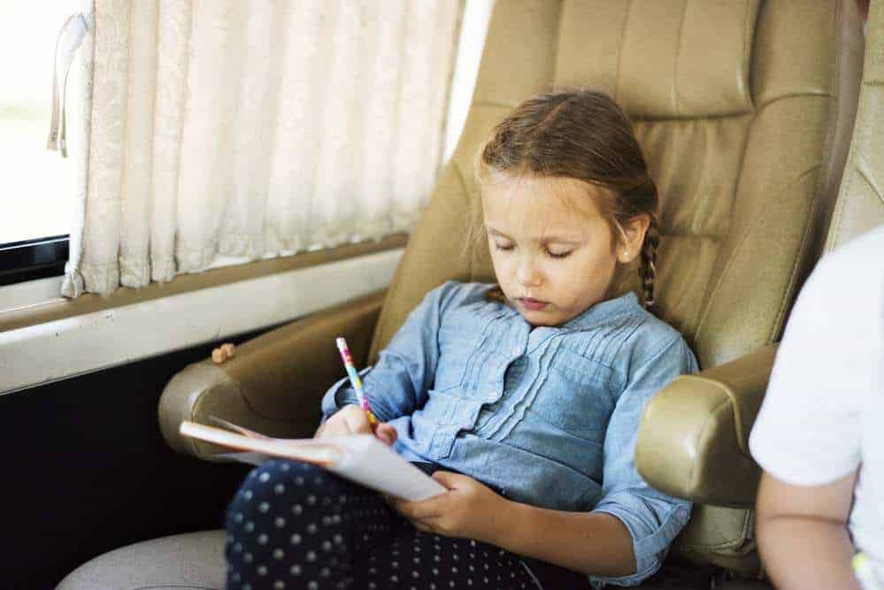 girl sitting in an RV chair writing in a book