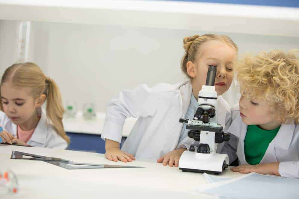  three children exploring hands-on science activities with a microscope