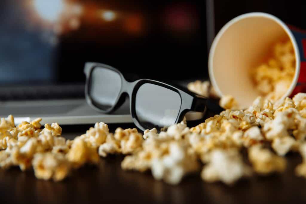 Popcorn and 3d glasses in front of laptop playing movie. Movie, fastfood. Entertainment concept.