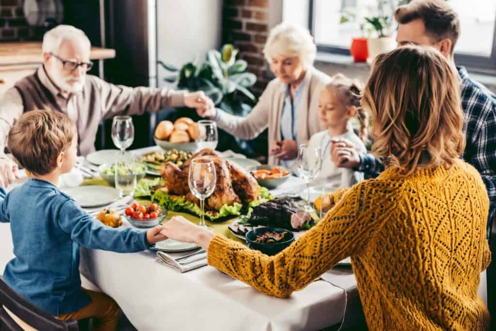 Family praying around Thanksgiving feast